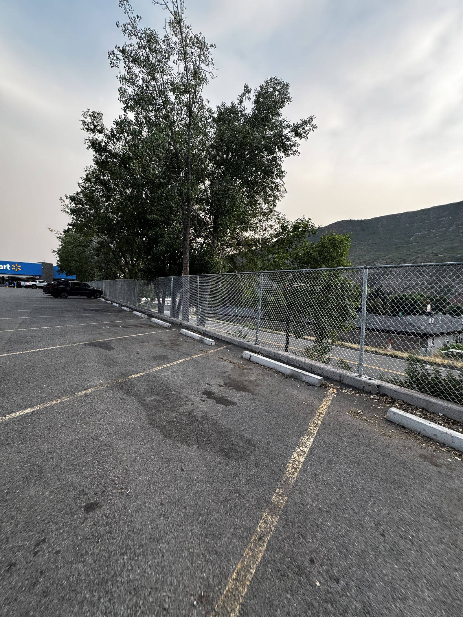 Long commercial chain-link fence run along a retail parking lot